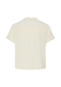 Blouse crème à manches courtes avec col à volants et détail plissé dans le haut du dos.