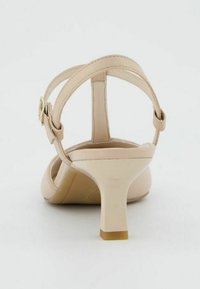 Sandale à talon haut beige avec une tige en cuir lisse, une bride de cheville ajustable et un talon effilé. Design minimaliste avec une finition brillante.