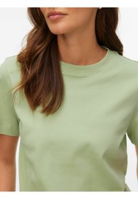 Lysegrøn kortærmet bomuldst-shirt med rund halsudskæring, glat tekstur og minimalistisk design, der fremhæver enkle linjer og syninger.