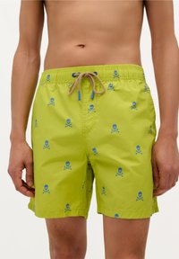Maillots de bain vert lime avec une taille à cordon de serrage, ornés de motifs de têtes de mort et os croisés bleus. Tissu léger à la texture lisse.
