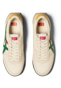 Sneakers con una toma superiore in tessuto color crema, strisce verde e rosse, collo imbottito e punta perforata. Suola in gomma con trazione.