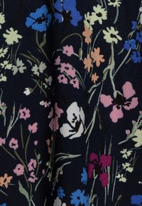 Blommig tyg med en mörk marinbakgrund och färgglada blommor i blått, rosa, vitt och gult, med gröna stjälkar och blad.