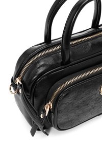 Zwarte leren handtas met dubbele ritscompartimenten, een gestructureerd oppervlak, gouden hardware-accenten en ronde handvatten. Compact ontwerp.