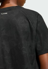 Black athletic t-shirt with textured camo pattern. Features breathable material, crew neck, and CLIMACOOL branding at the upper back.