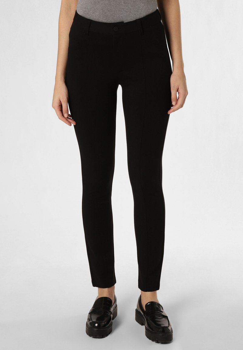 Pantalons noirs ajustés en tissu extensible, présentant des poches, une taille mi-haute et une texture lisse, associés à des mocassins noirs.