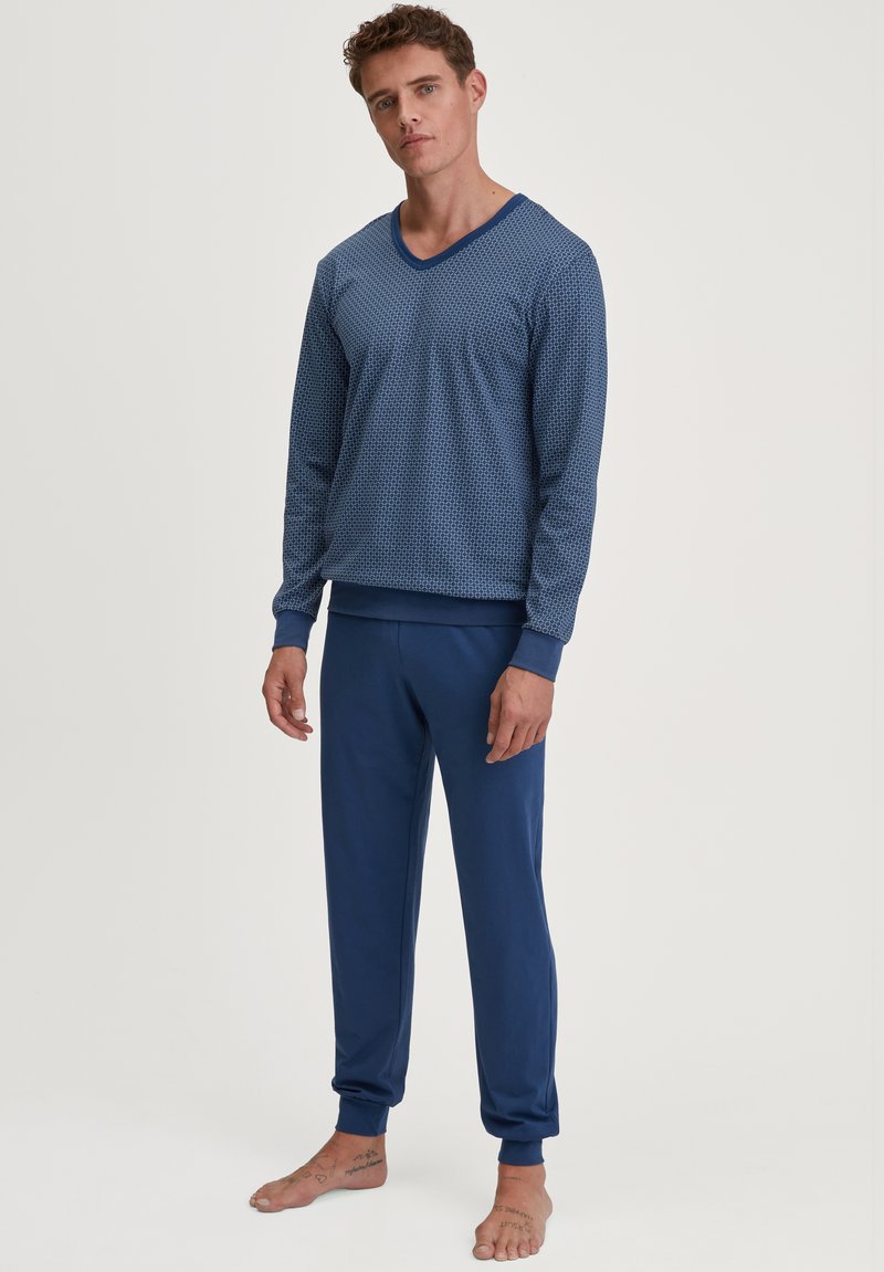 Blauw pyjama set bestaande uit een gestreepte langslijf top met een V-hals en bijpassende effen kleur broek met geribbelde boorden. Katoenen materiaal.