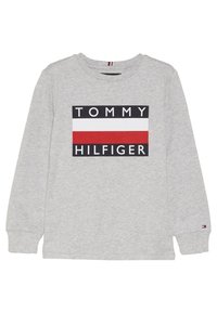 Graues Langarm-T-Shirt mit einem großen "TOMMY HILFIGER" Logo in schwarz, weiß und roten Streifen über der Brust. Weiches Baumwollmaterial.