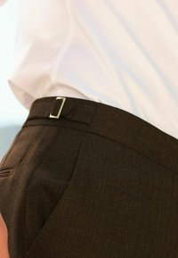 Brune, strukturerede bukser med en slim fit, der har en elegant talje og en subtil glans. Inkluderer en metal bæltesløjfe detalje.
