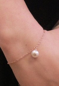 Bracciale a catena in oro rosa con un pendente di perla bianca, che presenta una superficie liscia e un design semplice ed elegante.