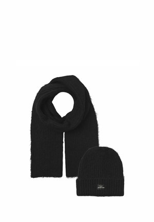 Sciarpa nera lavorata a maglia avvolta insieme a un berretto nero abbinato con una piccola etichetta rettangolare sul davanti.