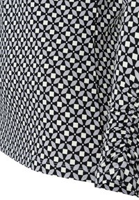 Musterstoff mit geometrischem Design in Schwarz, Weiß und Hellgrau. Glatte Textur mit gerafften Details entlang der Kante.