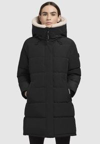 Schwarze Daunenjacke mit hohem Kragen, weicher Fütterung und Fronttaschen. Mit einem Reißverschlussverschluss und einem gesteppten Muster.