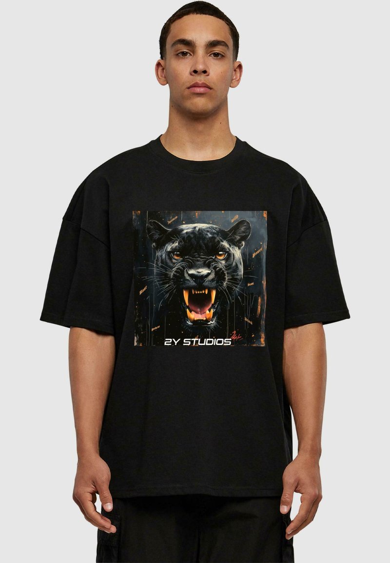 Fekete, túlméretezett póló, középre nyomtatva egy ordító fekete párduc grafikájával, narancssárga kiegészítőkkel, puha anyagon.