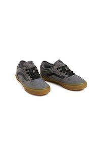 Zapatillas bajas de ante gris con cordones negros, que presentan una parte superior texturizada y una suela de goma. Destacadas con el logo en la lengüeta y el lateral.