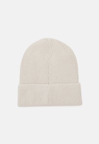 Gorro de punto en beige claro, con textura acanalada, dobladillo enrollado y parte superior ligeramente alargada para un ajuste ceñido.