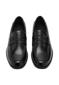 Mocasines de cuero negro con un acabado suave, que presentan una correita decorativa a lo largo del empeine y sutilezas de costura a lo largo de los bordes.
