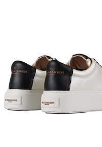 Sneaker platform bianche con accenti in pelle nera, caratterizzate da una superficie testurizzata, un'etichetta sul tallone con il marchio e dettagli di cuciture a contrasto sui lati.