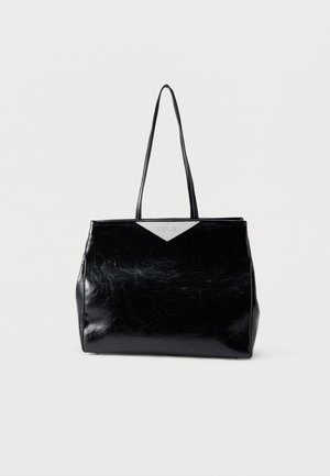 Zwarte glanzende leren handtas met lange handvatten en een driehoekig zilveren detail nabij het midden bovenaan, tegen een effen witte achtergrond.