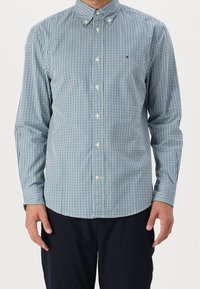 Camicia button-up a quadri verde e blu navy realizzata in un tessuto dalla texture liscia, dotata di colletto e bottoni bianchi.