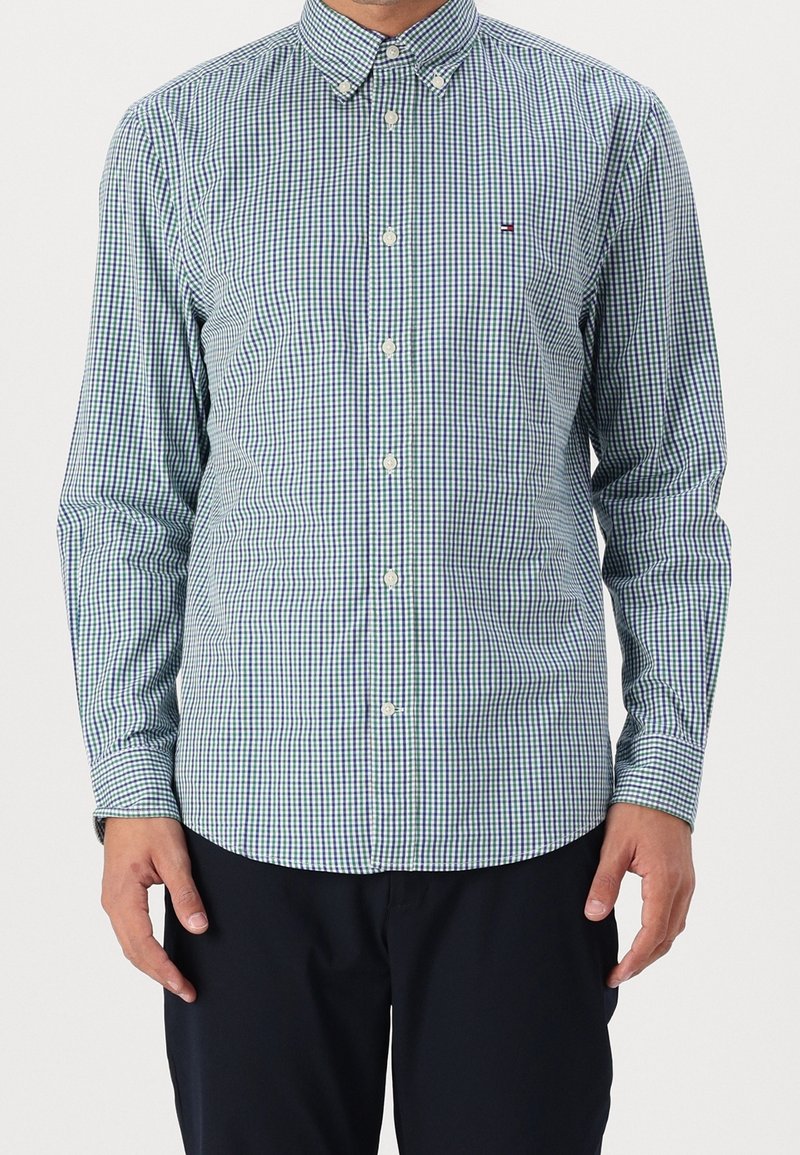 Camicia button-up a quadri verde e blu navy realizzata in un tessuto dalla texture liscia, dotata di colletto e bottoni bianchi.