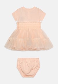 Brzoskwiniowa sukienka z krótkimi rękawami, falbankową spódnicą z tiulu i elastycznym paskiem w talii. Zawiera dopasowane brzoskwiniowe bloomersy. Wykonana z miękkiej mieszanki bawełny.