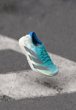 Een lichtgewicht sportschoen met een turkoois en grijs verloop bovenwerk, een textuurafwerking en een witte zool met groene accenten.