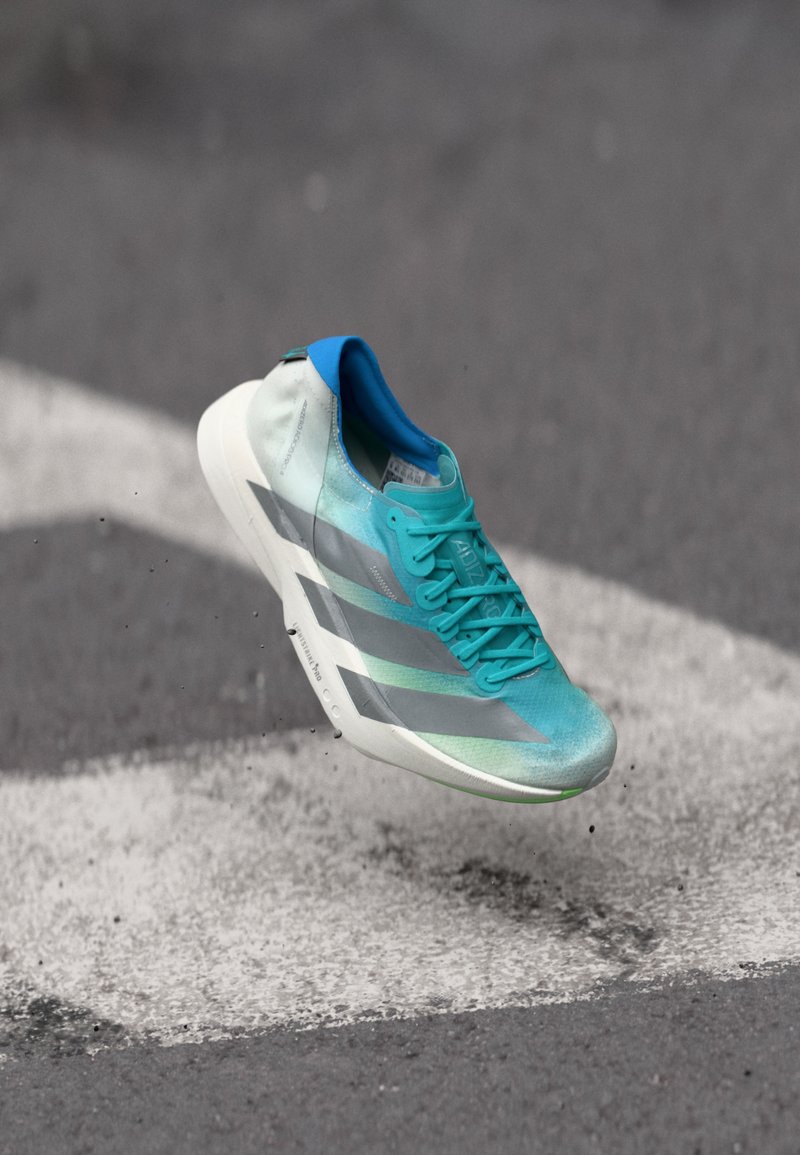 Ένα ελαφρύ αθλητικό παπούτσι με επάνω μέρος σε αποχρώσεις τιρκουάζ και γκρι, με υφή, και λευκή σόλα με πράσινες λεπτομέρειες.