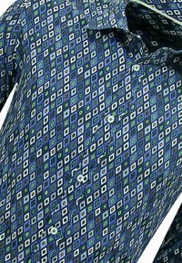 Korte mouw shirt van blauwe stof met een geometrisch diamantpatroon in tinten groen, wit en bruin met kleine knopen.