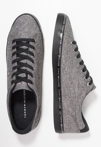 Sneakers in canvas grigio con lacci neri, punta rotonda, suola piatta e logo Tommy Hilfiger sul lato. Tessuto leggero e testurizzato.