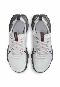 Witte sportieve schoenen met een bovenwerk van mesh, een zwarte rubberen zool en grijze accenten. Kenmerken zijn onder andere contrasterende oranje stiksels en veters.