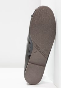 Chaussure en cuir verni noir avec une semelle en caoutchouc marron texturée présentant un motif en zigzag et un marquage. Taille 37 affichée sur la semelle.