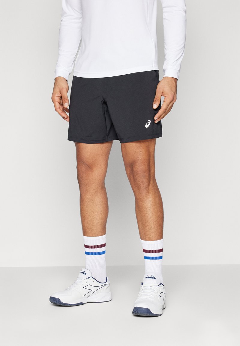 Schwarze Sportshorts aus leichtem Material, kombiniert mit weißen Socken, die blau- und bordeauxfarbene Streifen aufweisen, sowie weißen Sportschuhen.