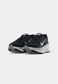 Adidași negri de alergare cu plasă în partea superioară, accente reflectorizante, logo-ul alb Nike swoosh și o talpă groasă gri cu model texturat pentru aderență.