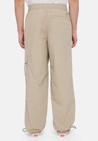 Beige cargo pants made of lightweight fabric, featuring a loose fit, side cargo pocket, and elastic waistband with drawstring.