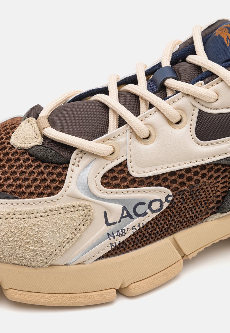 Brązowe i kremowe sneakersy z siateczkowym wzorem, zamszowymi akcentami, wytłoczonym logo oraz beżową gumową podeszwą o zaokrąglonych krawędziach.