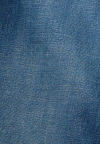 Denimtyg i en medelblå färg, med en klassisk twillväv, lätt textur och subtila nyansvariationer.