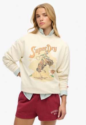 Crème sweatshirt met retro grafisch ontwerp van een cowboy op een paard, gecombineerd met bordeauxrode shorts. Getextureerde stof met cuffaccenten.