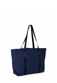 Námořnická modrá taška vyrobená z pevné textilie, s dvojicí dlouhých uší a jednoduchým obdélníkovým tvarem. Ozdobena logem na přední straně.