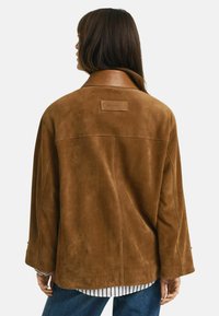 Giacca in suede marrone con vestibilità ampia, grande colletto e patch con il logo GANT sul retro. Superficie testurizzata e maniche lunghe.