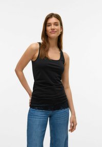 Schwarzes Tanktop aus weichem Material, mit quadratischem Ausschnitt und Spitzensaum, kombiniert mit hellblauen weit geschnittenen Jeans.