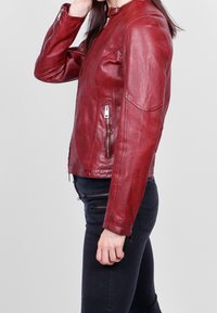 Chaqueta de cuero roja con bolsillos frontales con cremallera, un escote redondo y textura suave. Diseño ajustado con un ligero acolchado en los hombros.