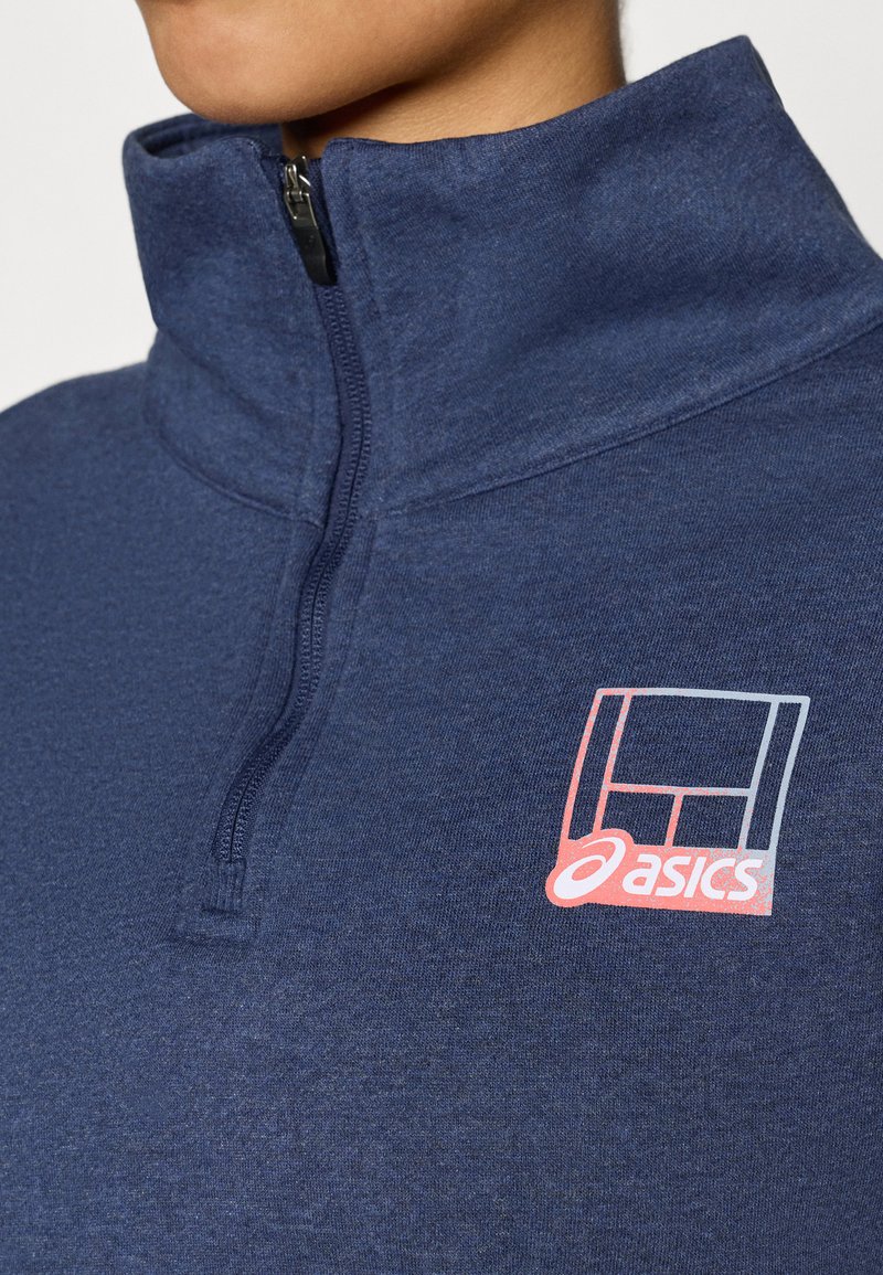 Marineblauwe fleece met kwartrits en hoge kraag, met een klein roze-wit Asics-logo op de borst. Zachte textuur en sportieve pasvorm.