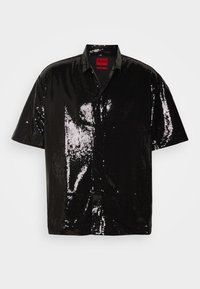 Chemise noire à manches courtes avec boutons, recouverte de sequins brillants, avec un petit col et une étiquette rouge "Hugo" à l'intérieur de l'encolure.