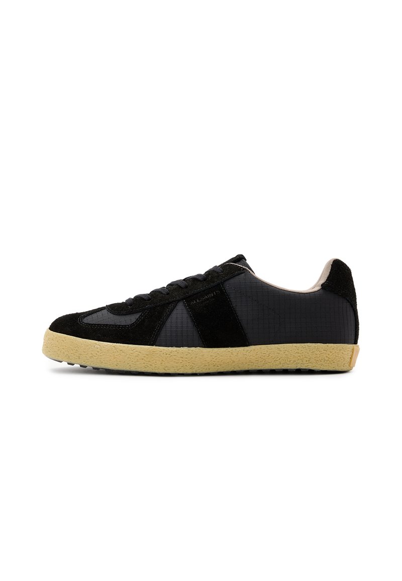 Baskets noires présentant une combinaison de textures lisses et en daim, un dessus texturé et une semelle en caoutchouc beige contrastée.