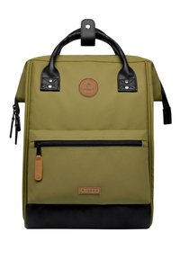 Sac à dos vert olive avec accents en cuir noir, poche zippée à l'avant, fond texturé et écusson rond. Comprend deux poignées supérieures et des bretelles ajustables.