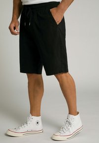 Sorte bomuldsshorts med elastisk talje, sidelommer og løs pasform, kombineret med hvide højdesko med røde accenter.
