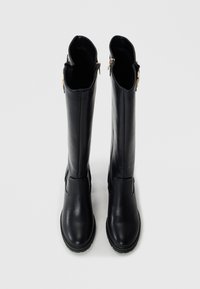 Bottes en cuir noir montantes avec une texture lisse, bout arrondi et accents de fermeture éclair latérale en ton doré. Design minimaliste avec une semelle robuste.