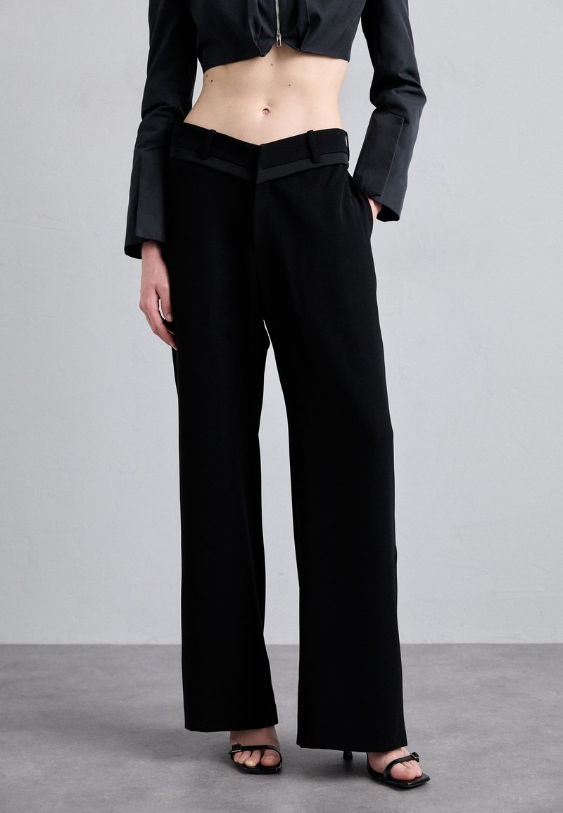 Black wide-leg trousers with a high waist, featuring a smooth fabric, belt loops, and a clean design for a tailored appearance.