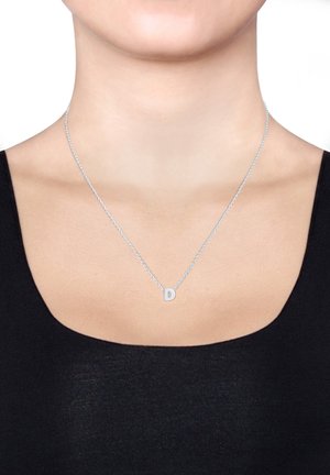 Silberne Kettenhalskette mit einem quadratischen Anhänger, der den Buchstaben "D" trägt. Die Kette ist fein verdreht und ergänzt das minimalistische Design.