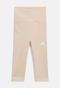 Bež bežne kratke legice z visokim pasom in belim logotipom Adidas na levi stegni, položene na ravno belo ozadje.